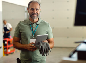 Hombre con camisa verde, sonriedo, usando una tablet.